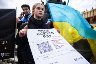 picture-alliance/NurPhoto/Beata Zawrzel Russland soll für die Kosten des Ukrainekriegs zahlen. Banner anlässlich einer Solidaritätskundgebung mit der Ukraine im Februar in Krakau, Polen.